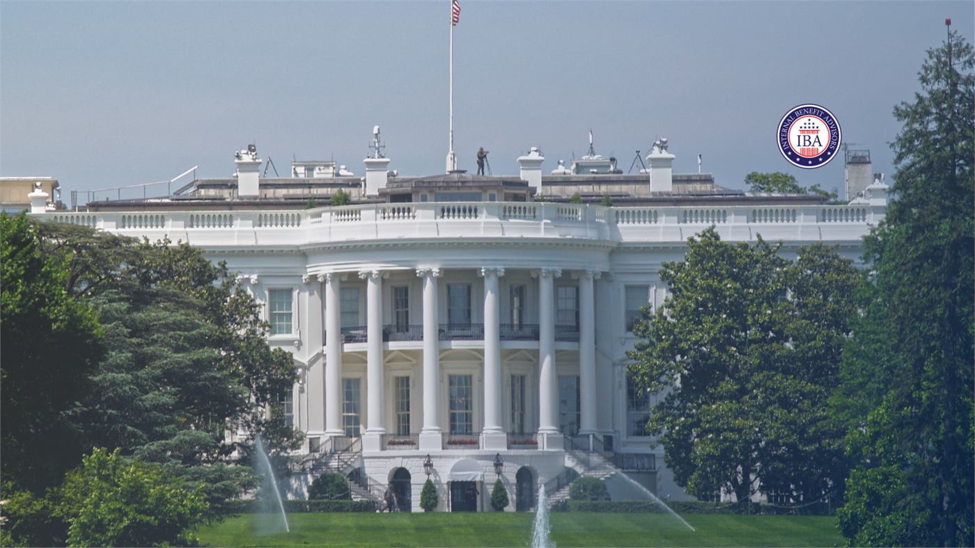 The north front of the White House, seen across the lawn and fountain through surrounding trees