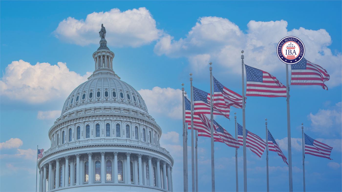 The United States Capitol dome under a blue sky, with a row of American flags flying in front of it