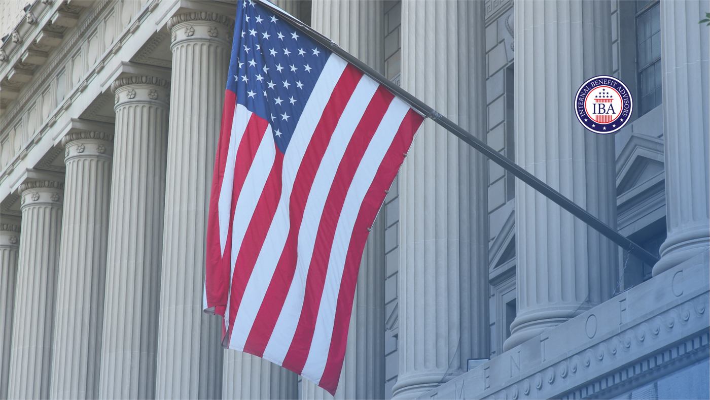 An American flag hanging from the facade of a classical government building with tall stone columns