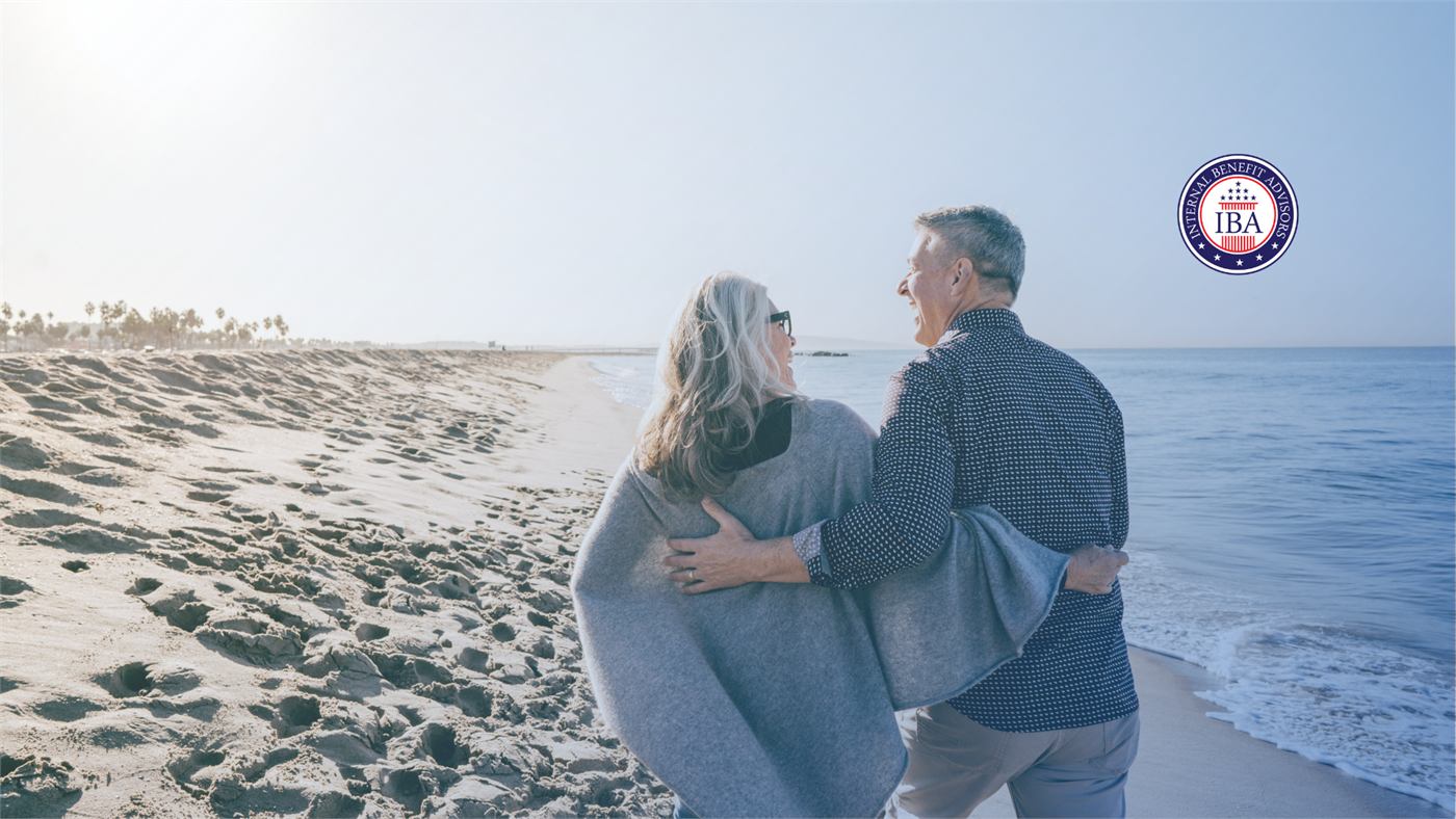 A couple standing together on a beach at dusk, wrapped in a blanket