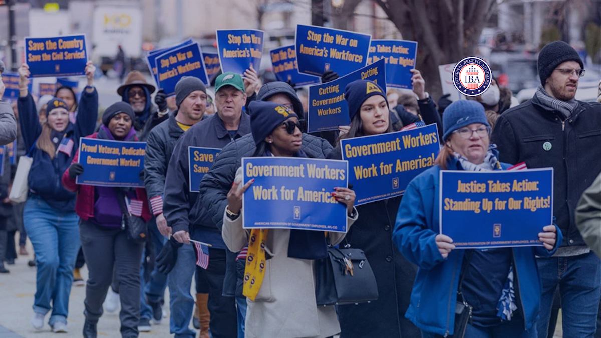 A crowd of demonstrators marching with placards reading Government Workers Work for America and Justice Takes Action, Standing Up for Our Rights