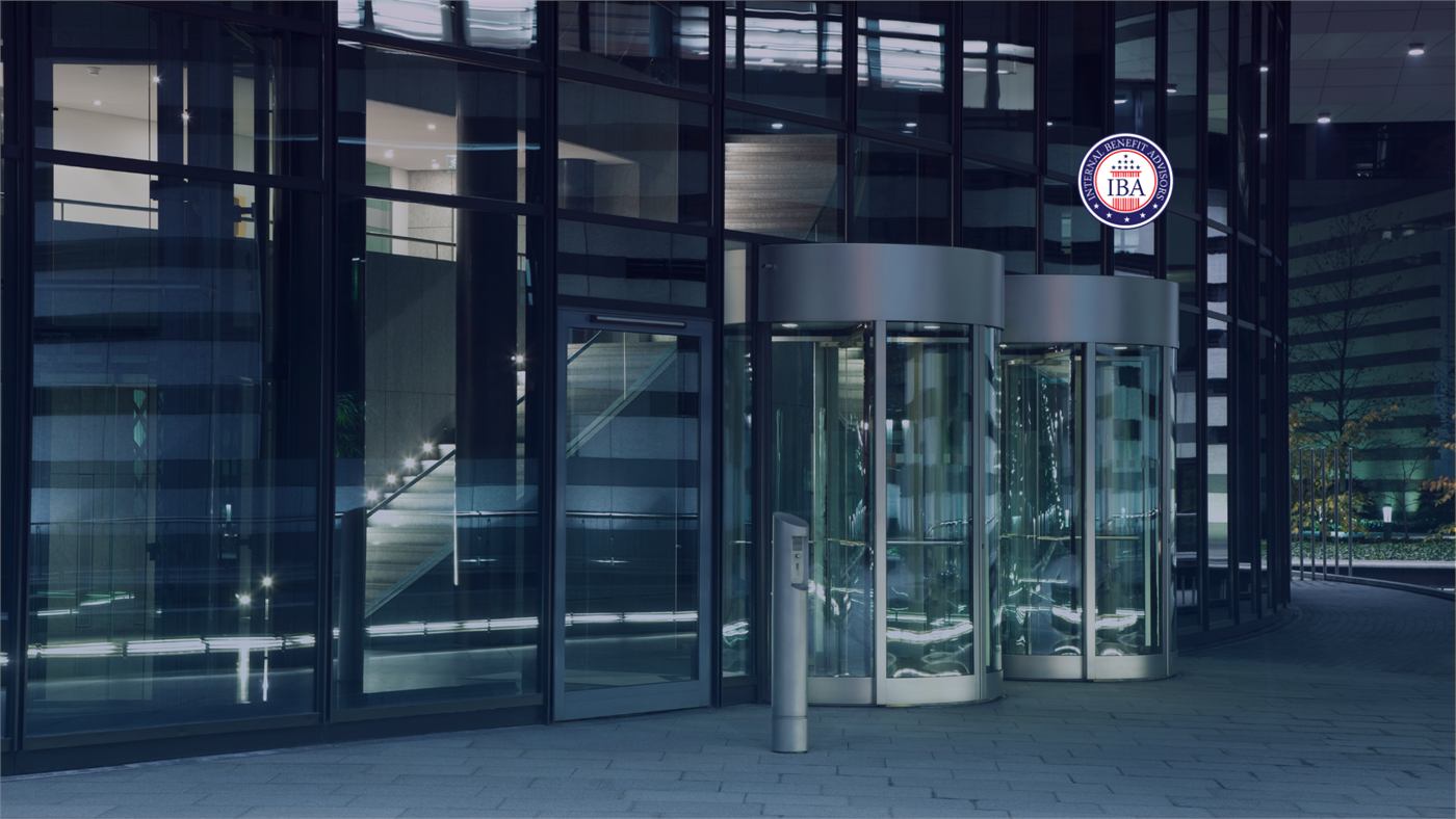 A revolving glass door at the entrance to a modern dark-glass office building