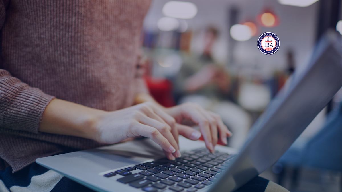 Close-up of a woman's hands typing on a laptop keyboard in a bright room