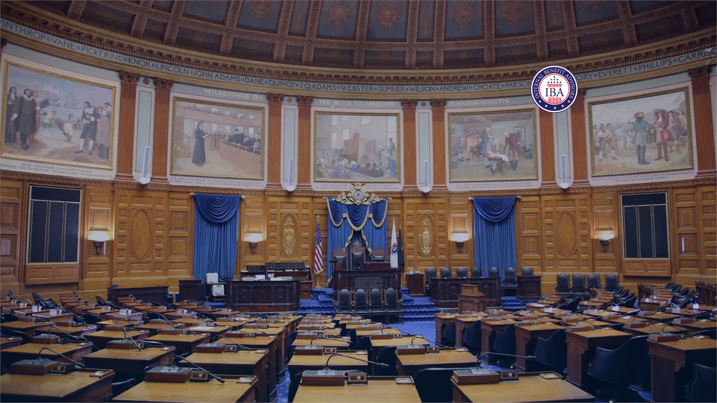 The interior of a domed legislative chamber, with rows of empty wooden desks facing the rostrum