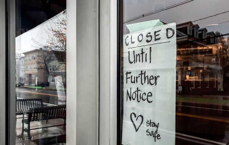 A handwritten sign in a shop window reading Closed Until Further Notice, Stay Safe