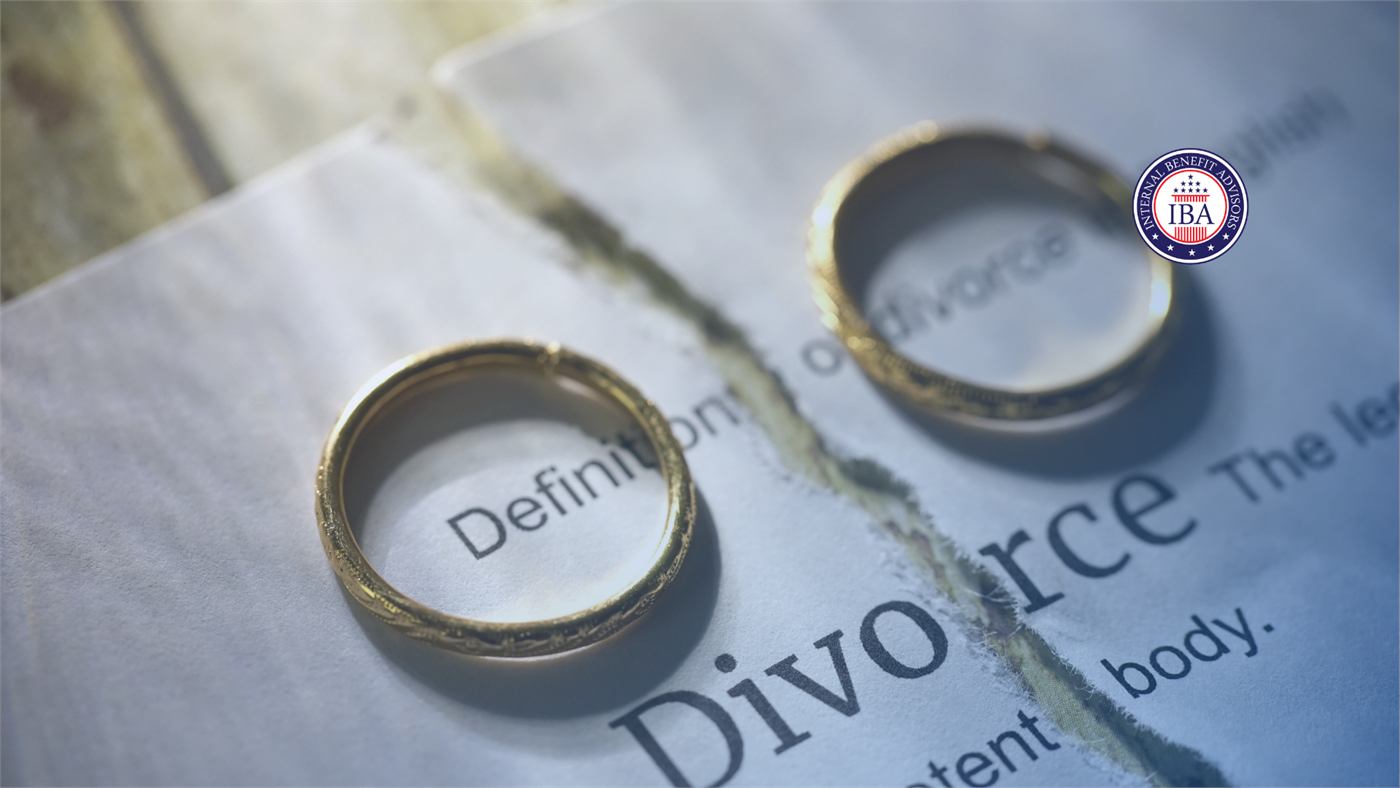 Two gold wedding rings resting on a torn dictionary page showing the word Divorce