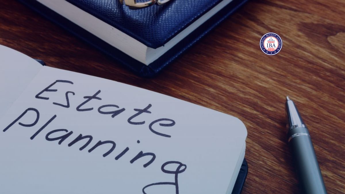 A notepad with Estate Planning written on it by hand, next to a pen and a bound book on a wooden desk