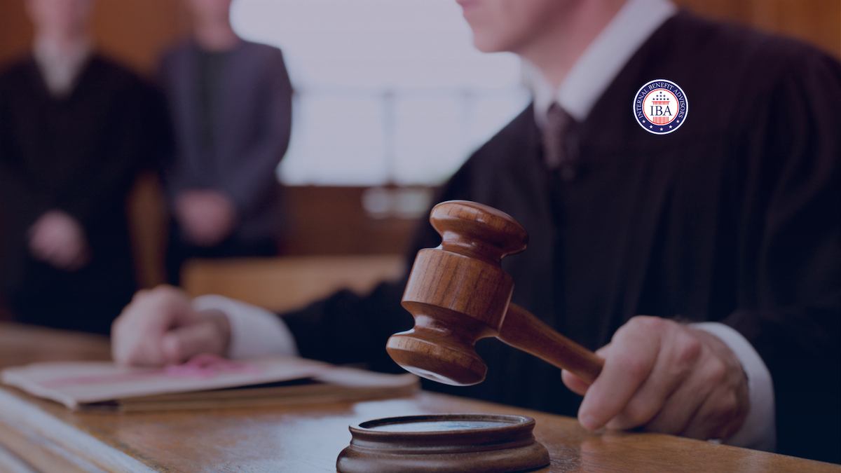 A judge in robes bringing down a gavel while people stand at the bench behind