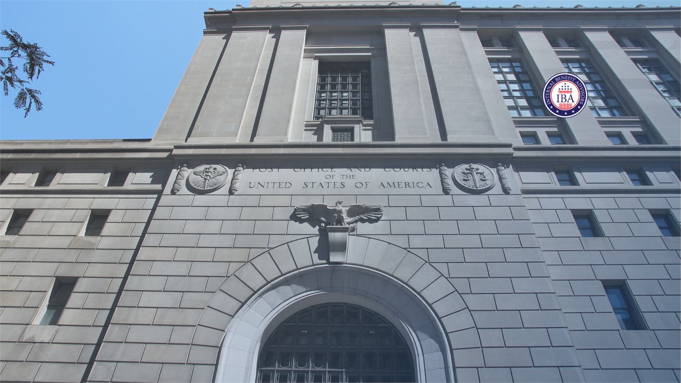 The stone facade of a United States federal courthouse with a large arched window