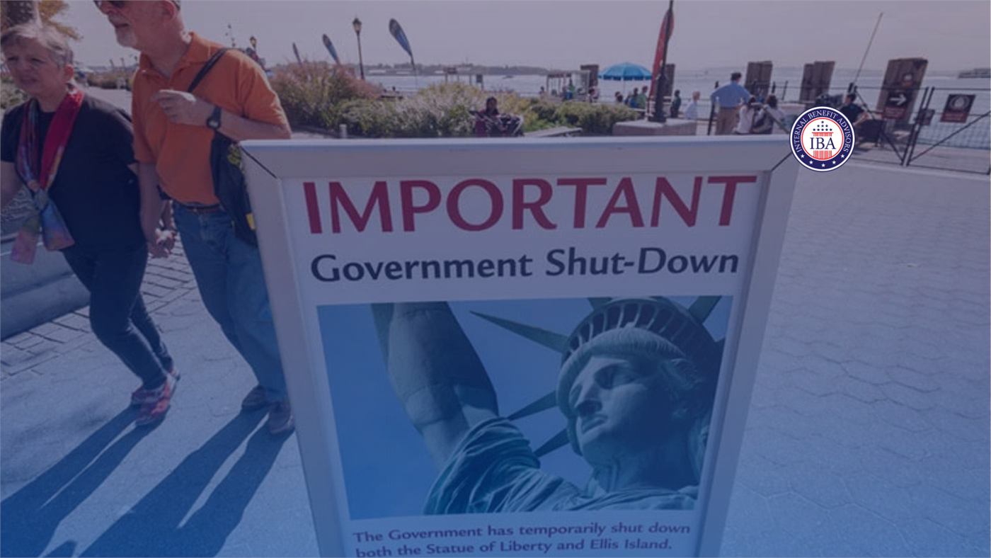 A poster reading Important Government Shut-Down displayed in front of the Statue of Liberty as visitors walk past