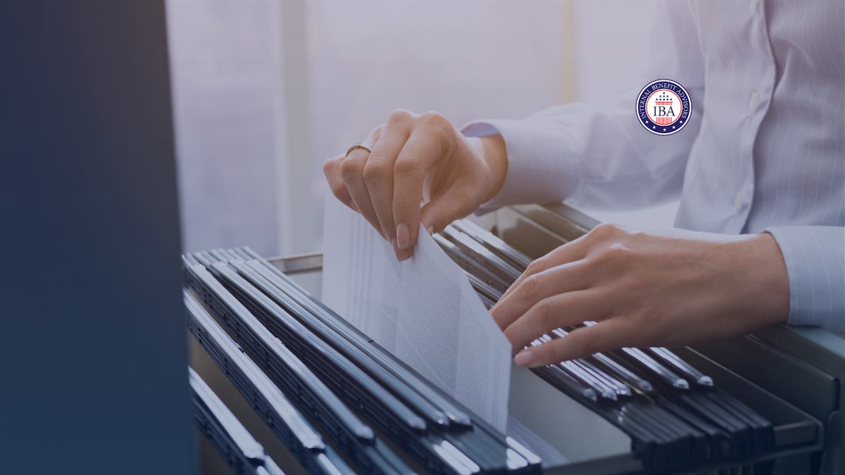 Hands searching through hanging files in an open filing drawer