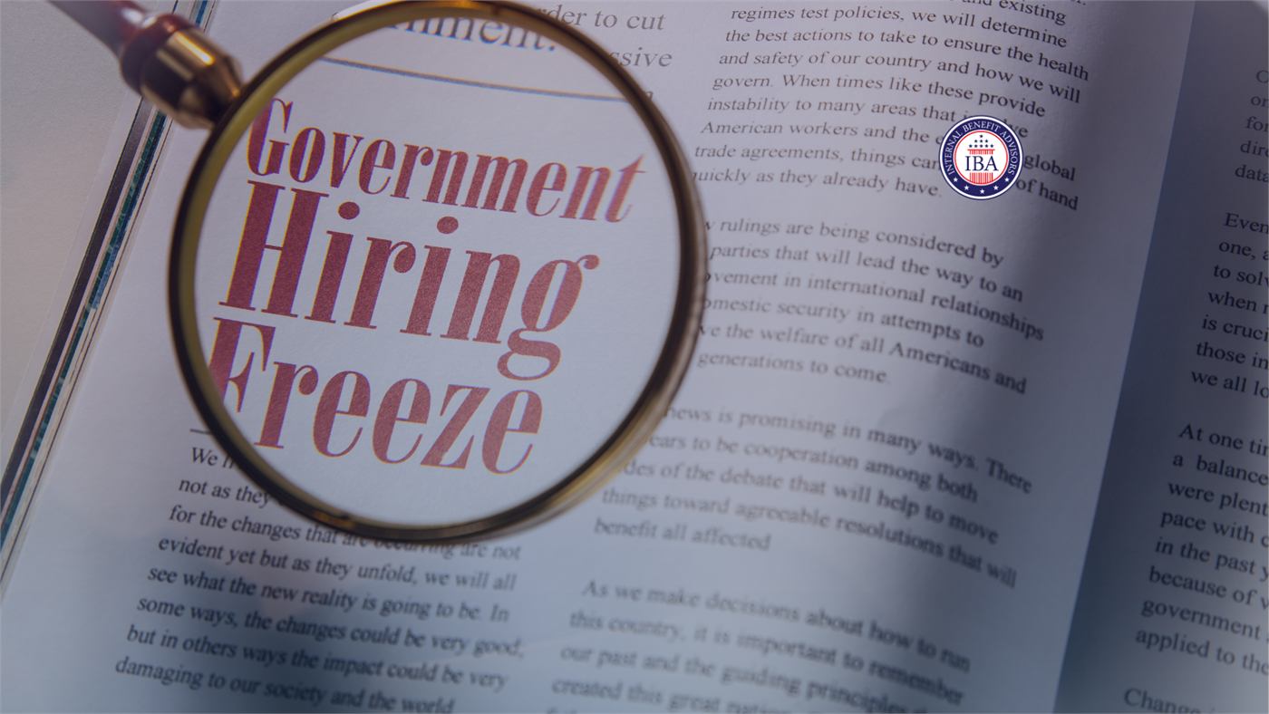 A magnifying glass held over a printed page, enlarging the words Government Hiring Freeze