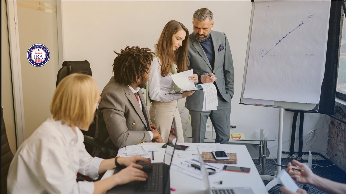 Colleagues gathered around a desk working through paperwork together in an office