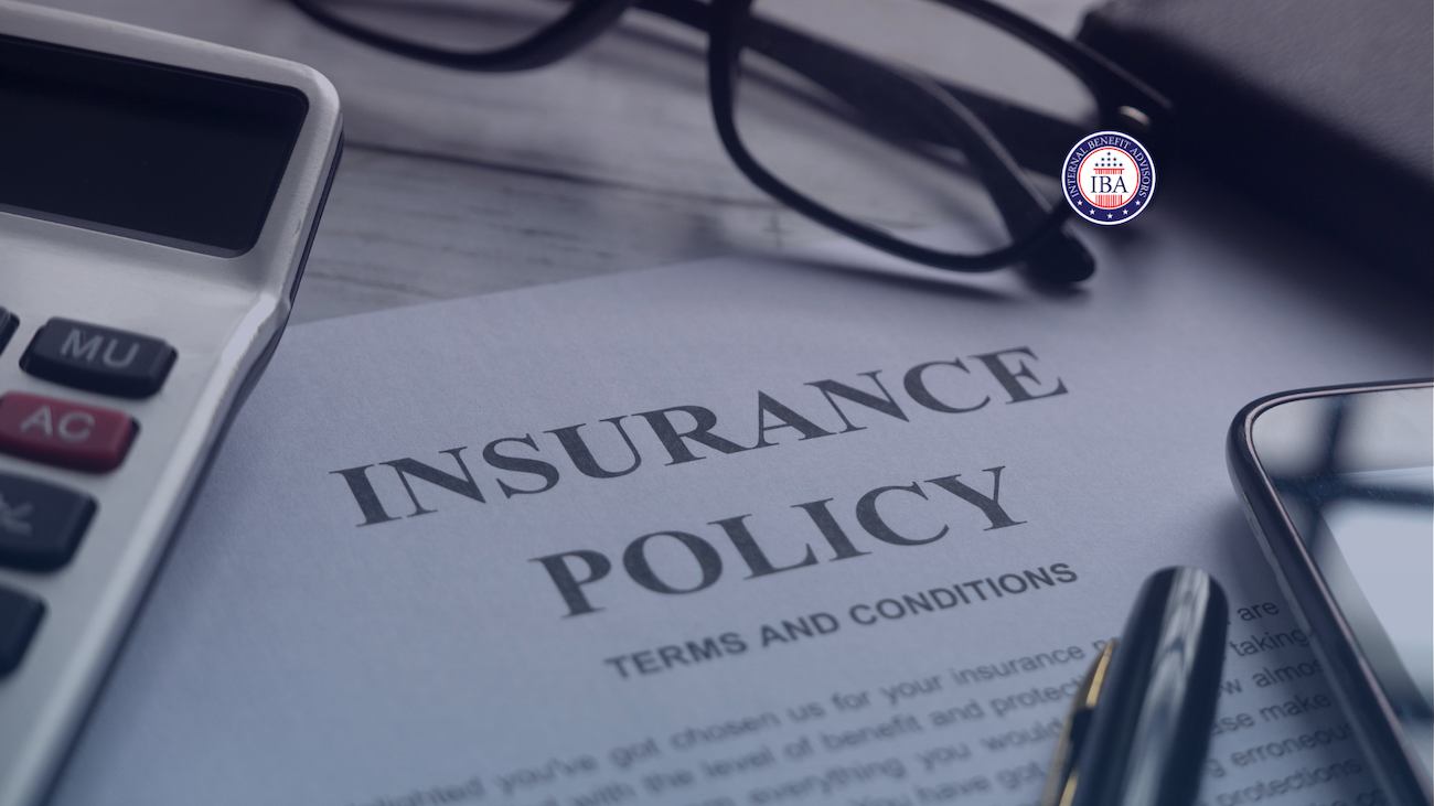 An insurance policy document showing terms and conditions, beside a calculator and pen