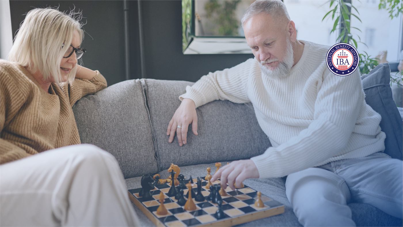 An older couple playing chess together on a sofa at home