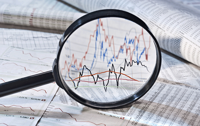 A magnifying glass held over a printed financial chart in a newspaper