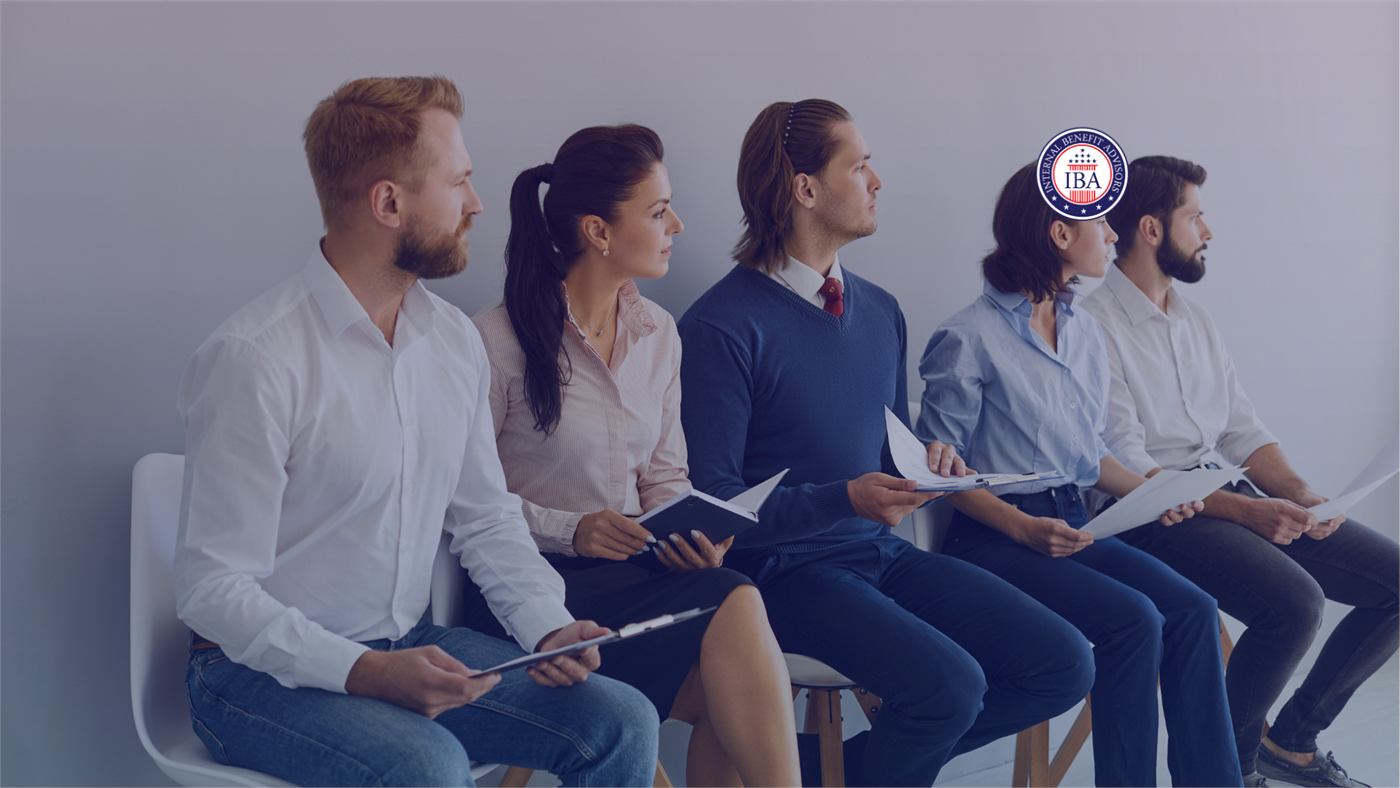 Five job candidates sitting in a row, waiting with documents in hand