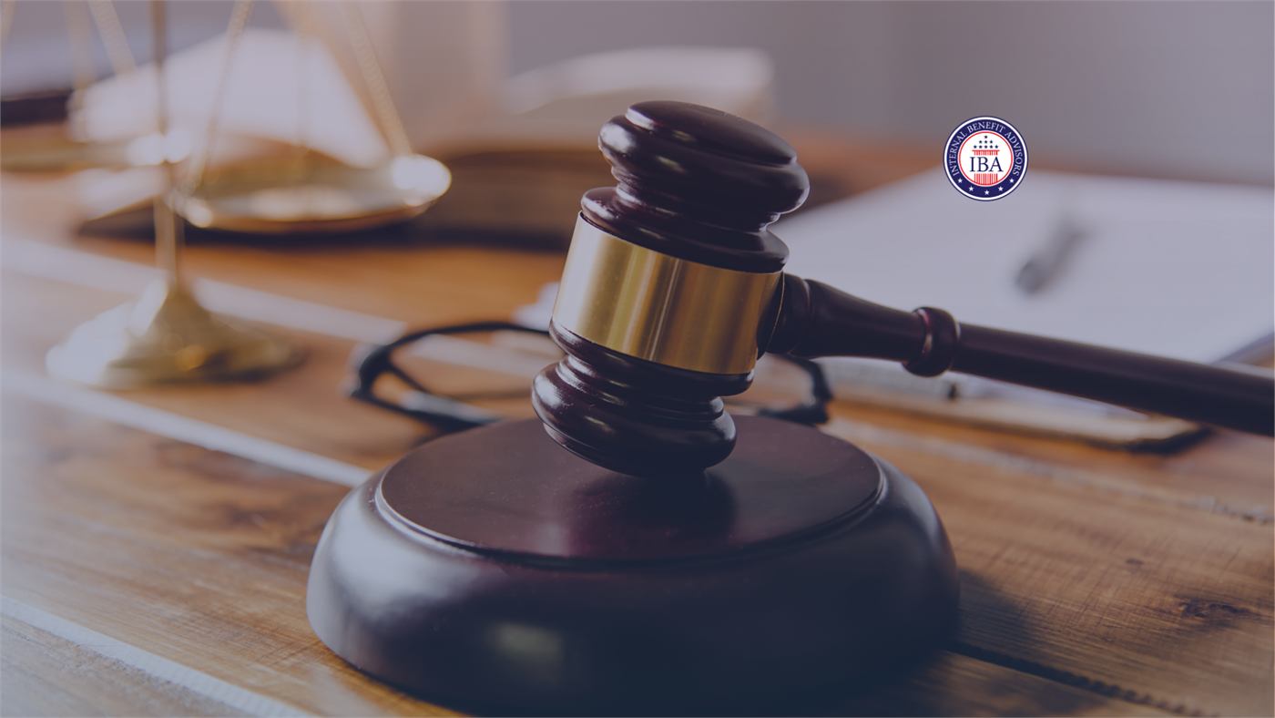 A wooden gavel on a desk beside brass scales of justice