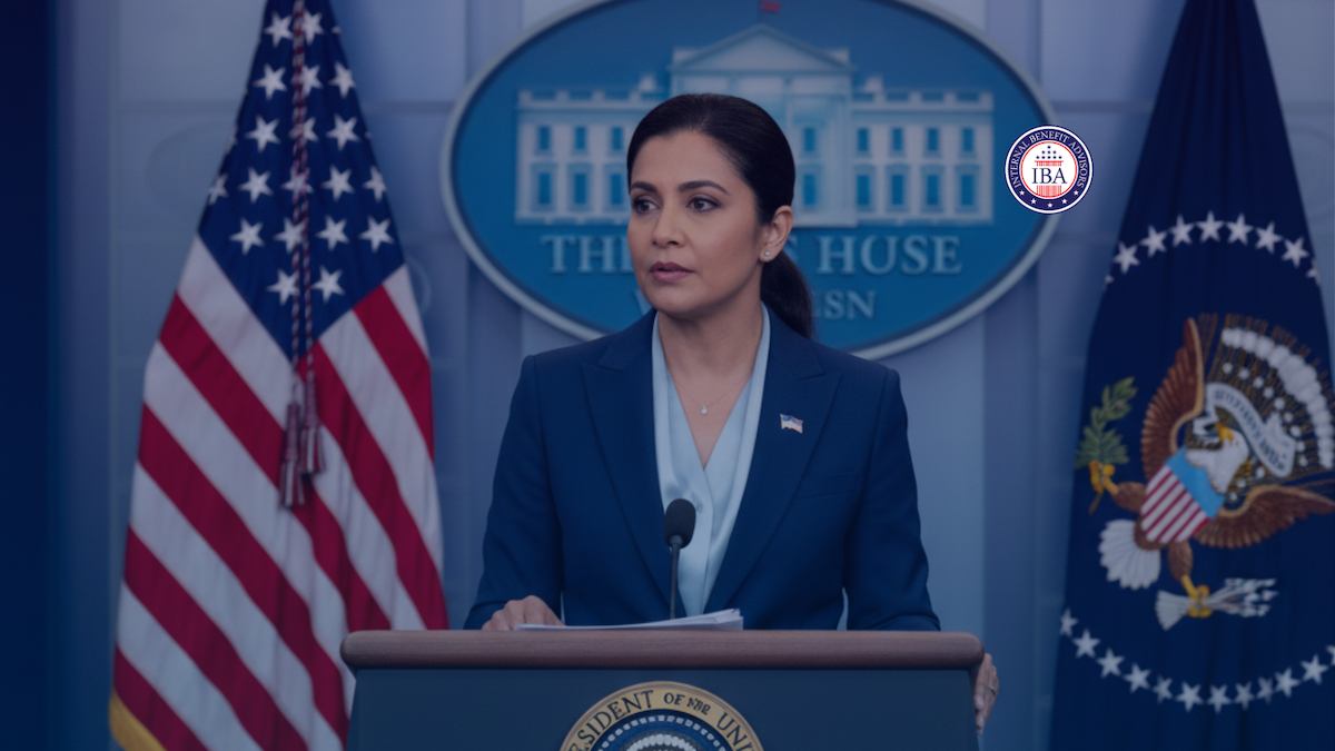A woman speaking at the White House press briefing podium between American flags