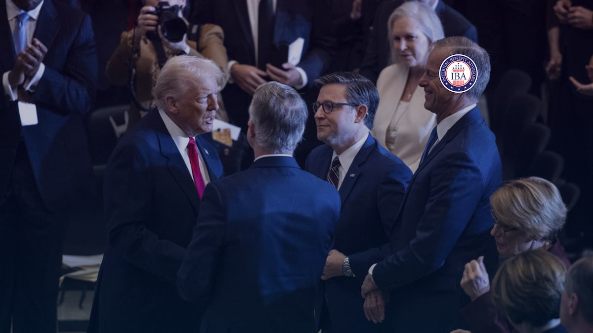 Politicians talking together in a crowded room, photographers behind them