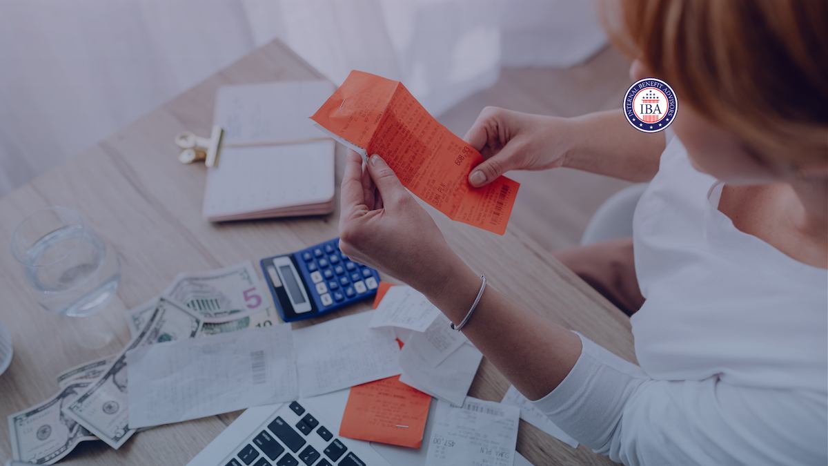 A woman opening a red payslip envelope at a desk with a calculator and banknotes