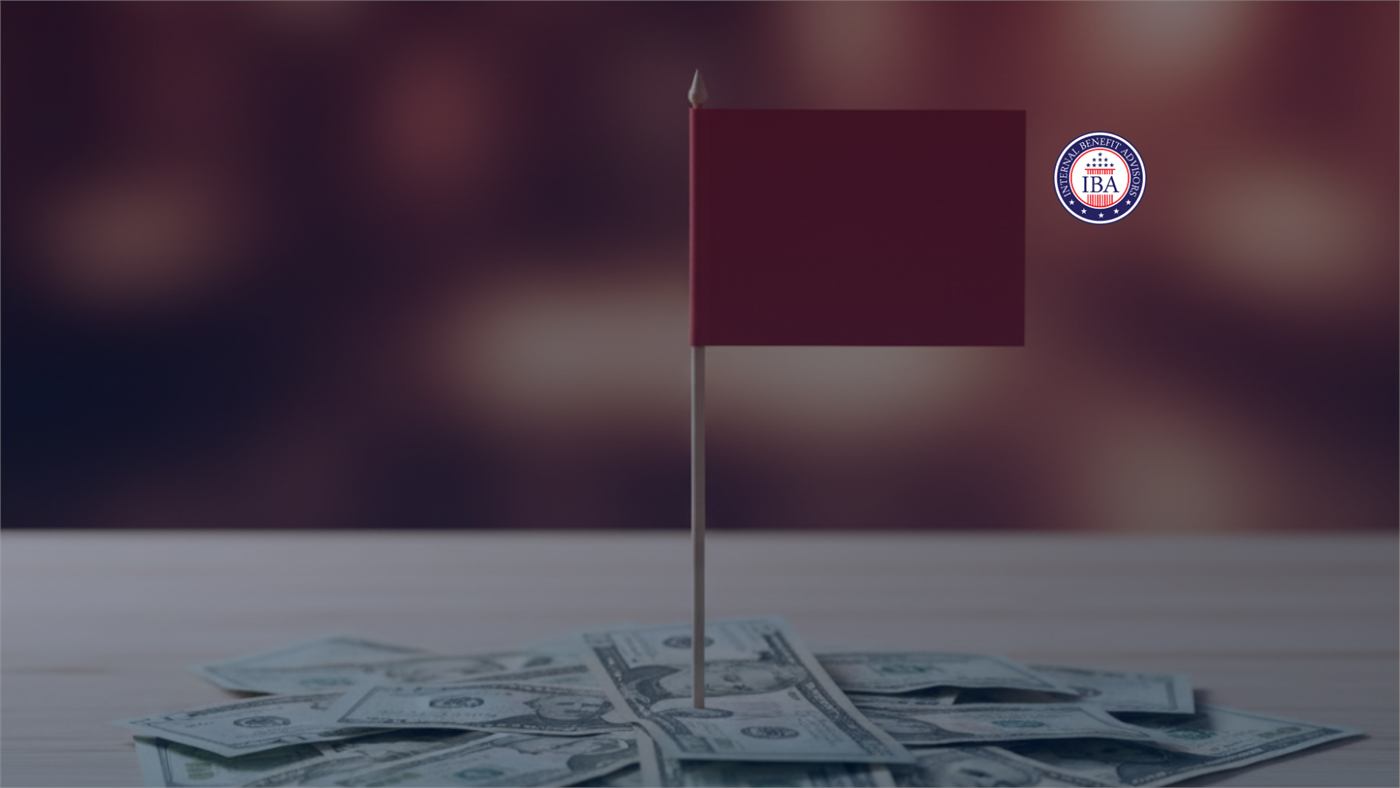 A small dark red flag planted in a pile of US banknotes