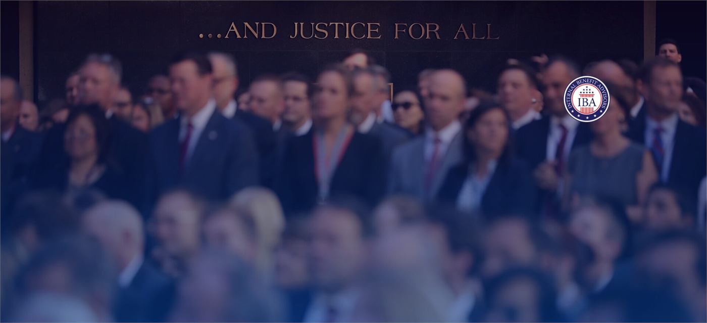 A crowd of people in a courthouse beneath the inscription And Justice For All