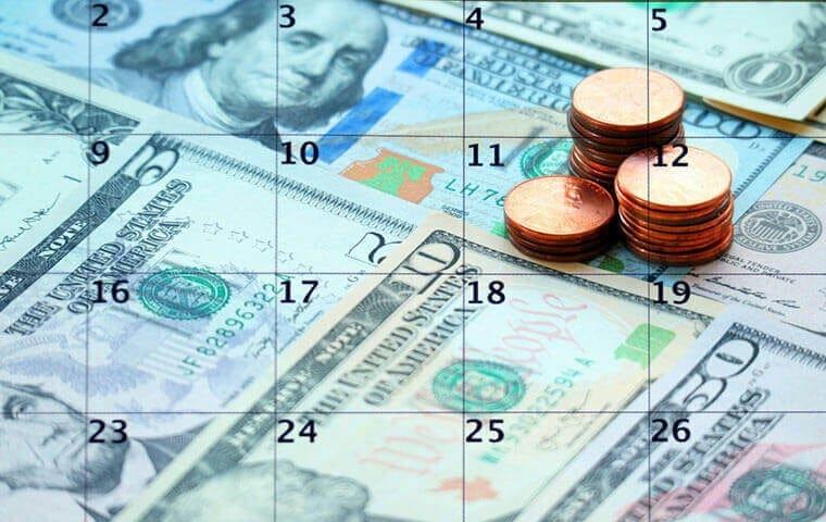 Coins stacked on a calendar page laid over US banknotes