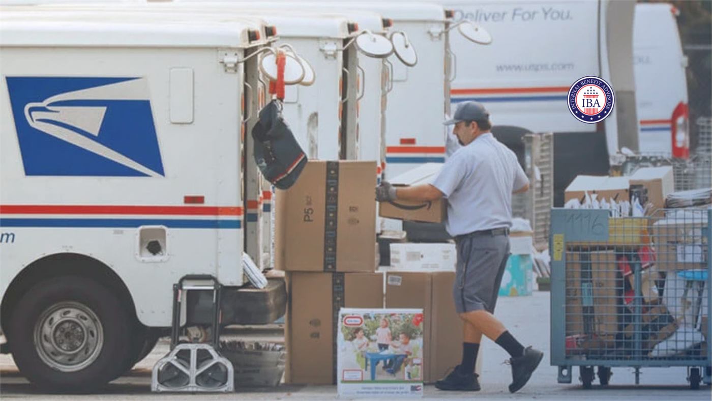 A postal worker loading parcels into USPS delivery trucks