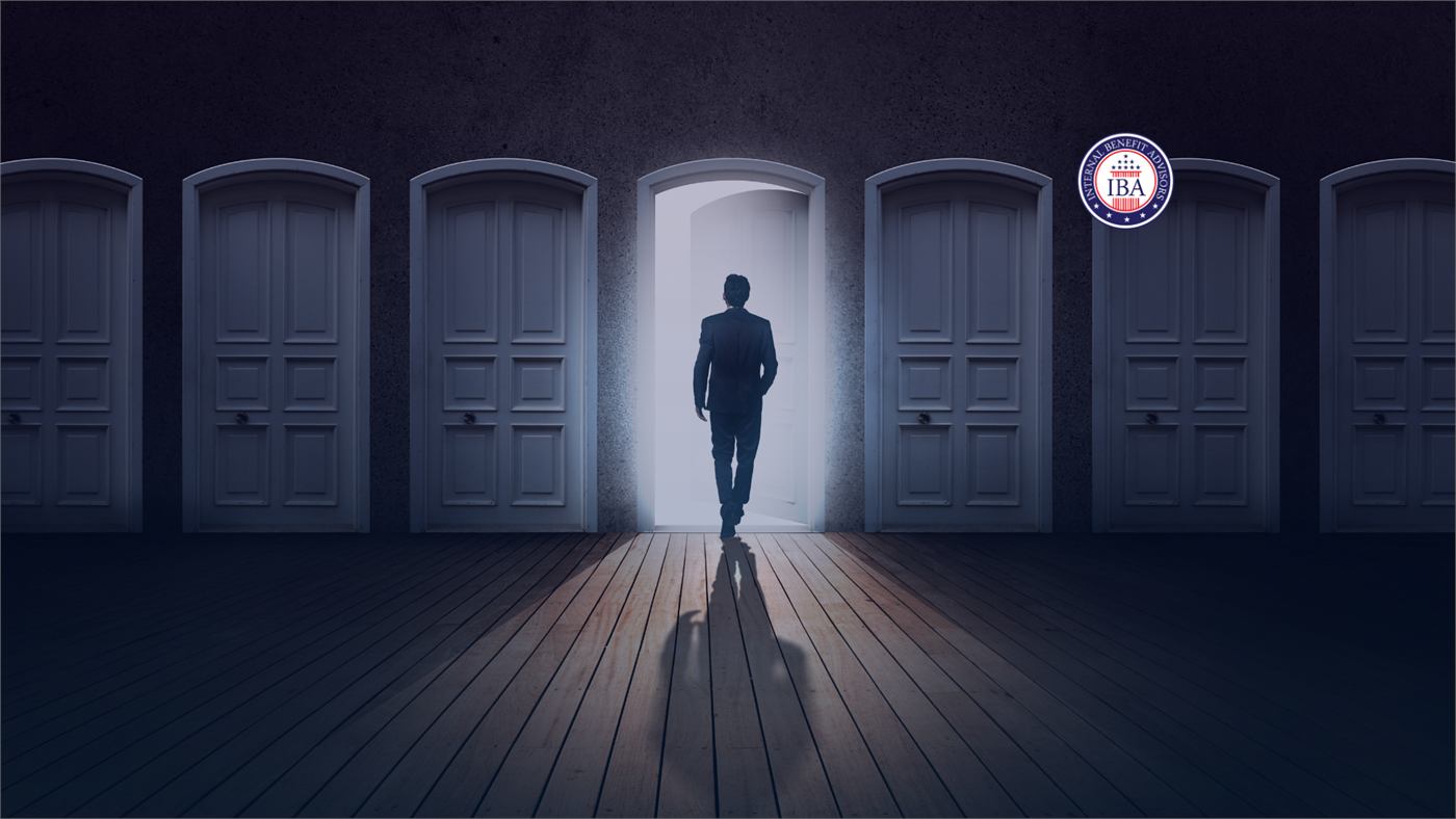 A silhouetted figure walking through the one open door in a corridor of closed doors