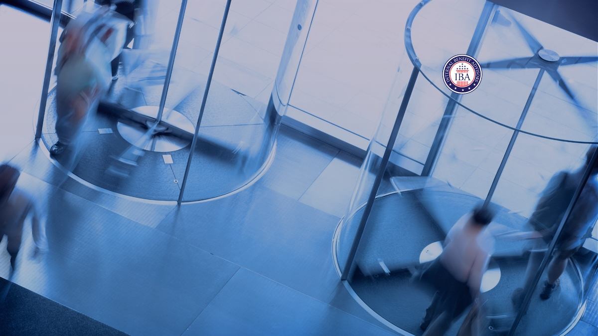 People passing through a revolving glass door in a bright office lobby