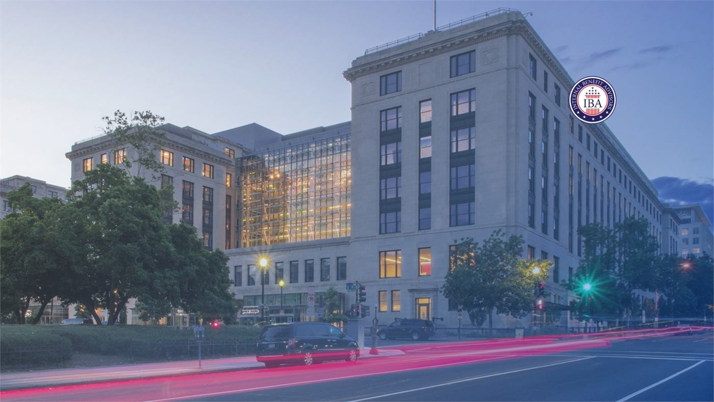A large federal office building lit at dusk beside a road