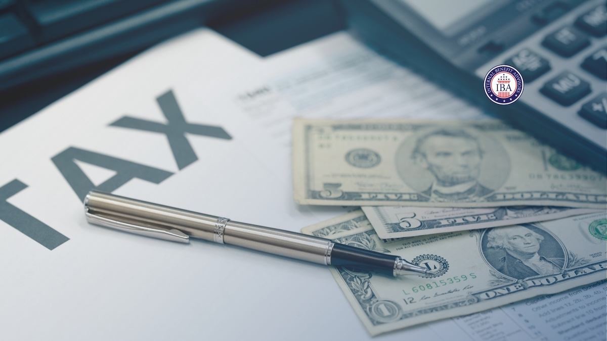 A document headed Tax with a pen and US banknotes resting on top